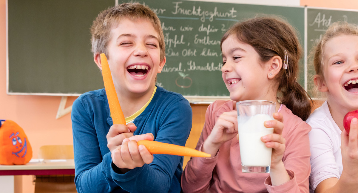 3 Kinder mit Karotte, Milchglas und Apfel